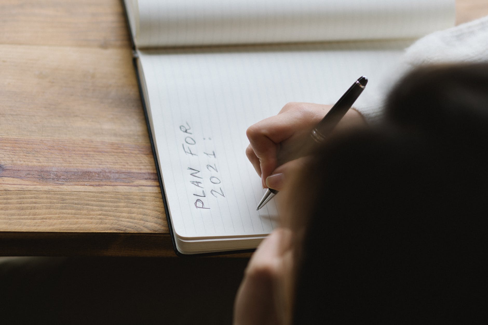 crop faceless woman writing plans in diary