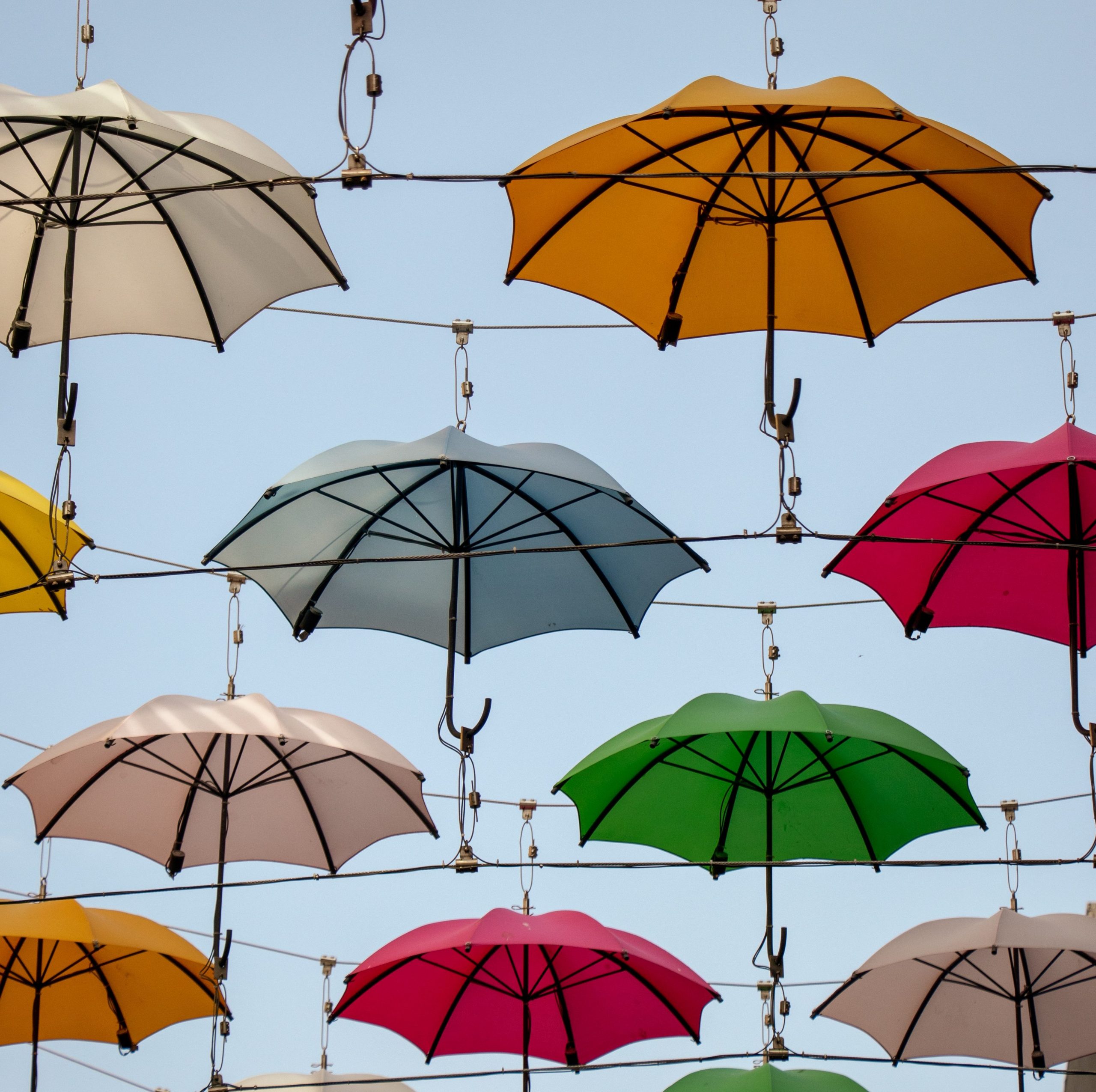 Una serie di ombrelloni colorati appesi con dei fili in cielo.
